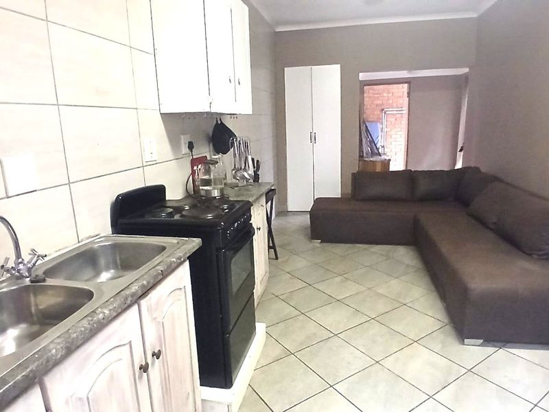 Open plan kitchen and living area featuring tiled flooring, built-in cabinetry, and a double bowl stainless steel sink.