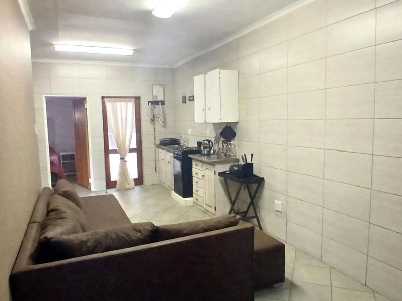 Open plan living and kitchen area featuring tiled walls and flooring, with basic built-in cabinetry and a freestanding stove.