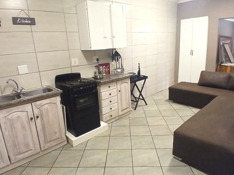 Open plan kitchen and living area featuring tiled finishes, built-in cabinetry, and a freestanding stove, offering a functional layout for daily living.