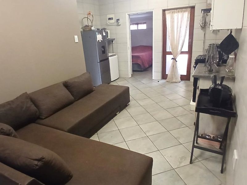 Open plan living area featuring tiled flooring and walls, with direct access to an adjacent bedroom.
