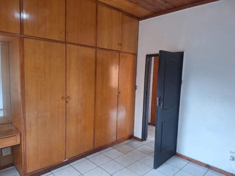 A bedroom featuring extensive built-in wooden cabinetry, a wooden ceiling, and tiled flooring, offering a functional space with potential for modern updates.