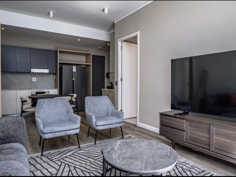 Modern open-plan living area featuring a contemporary kitchen with sleek cabinetry and integrated appliances, flowing seamlessly into a comfortable lounge space.