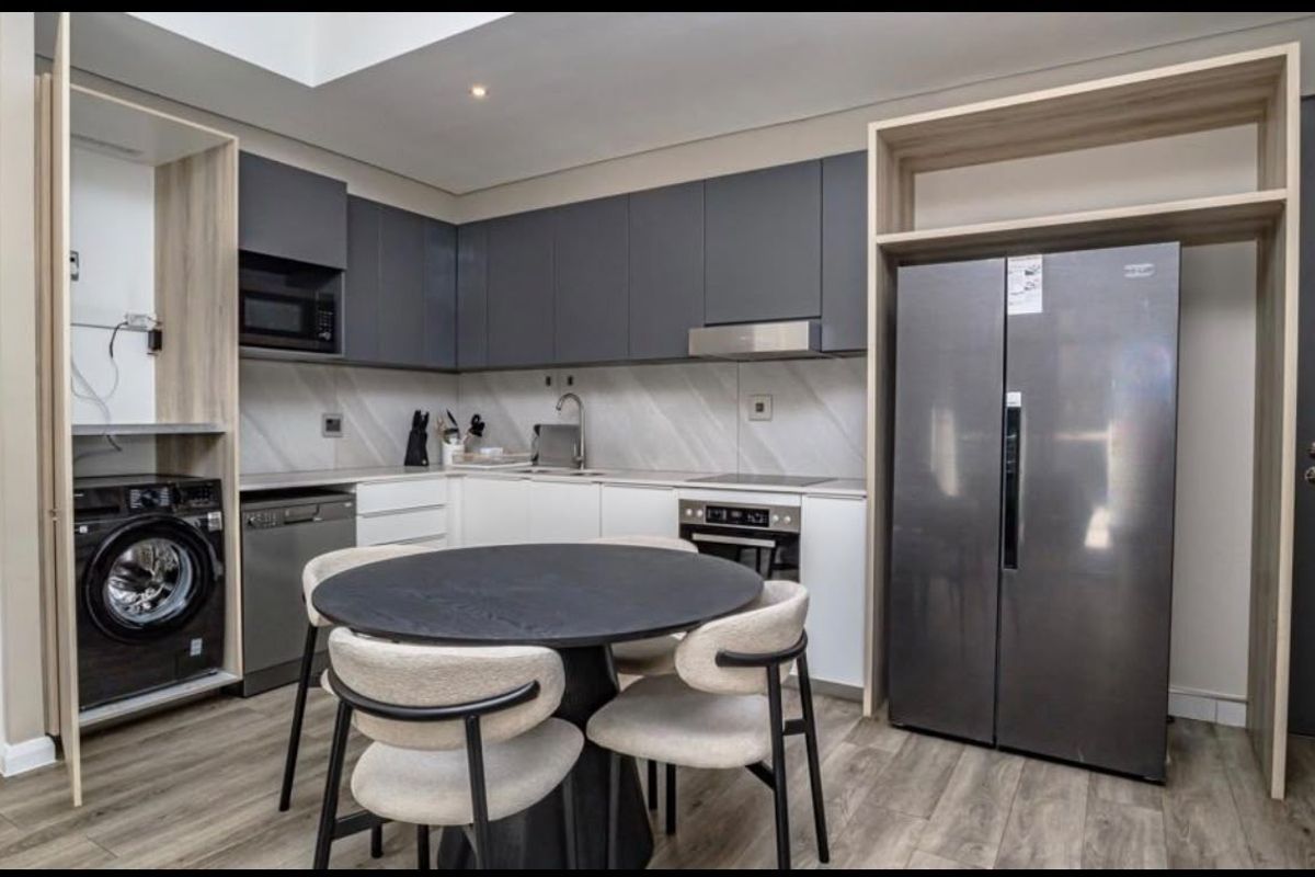 Modern kitchen featuring sleek two-tone cabinetry, integrated appliances, built-in laundry nook, and high-quality finishes throughout.