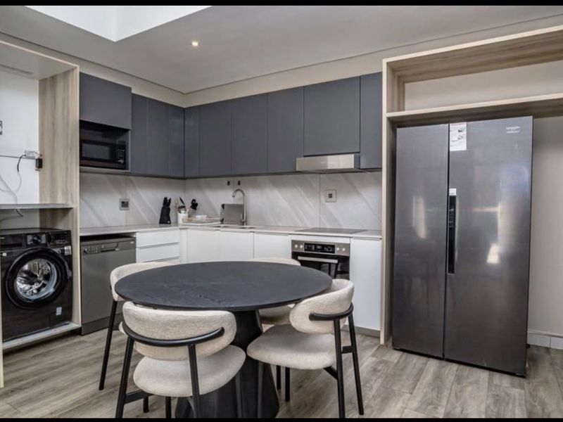 Modern kitchen featuring sleek two-tone cabinetry, integrated appliances, built-in laundry nook, and high-quality finishes throughout.