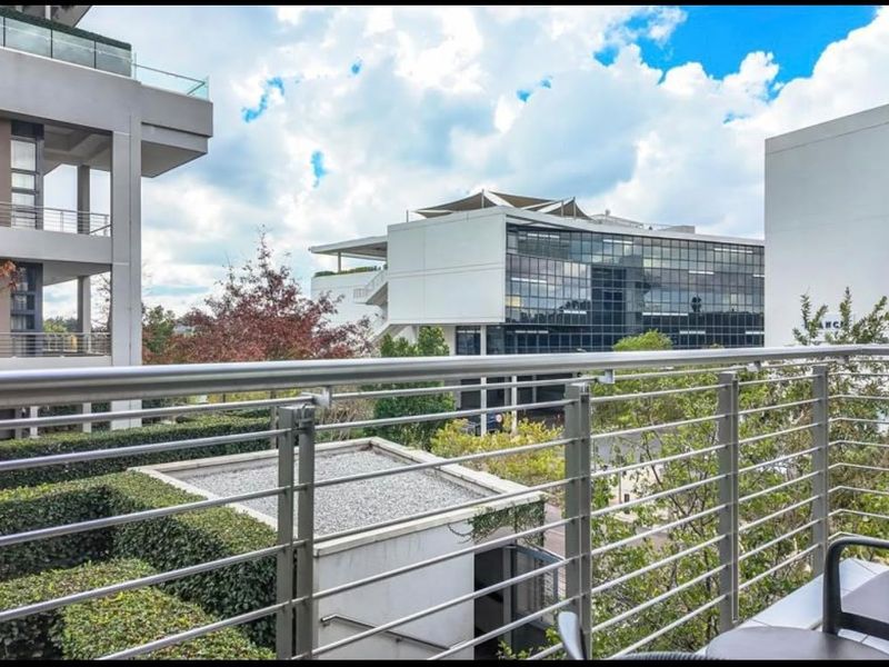 A modern apartment balcony featuring a sleek stainless steel balustrade and views of the surrounding urban landscape.