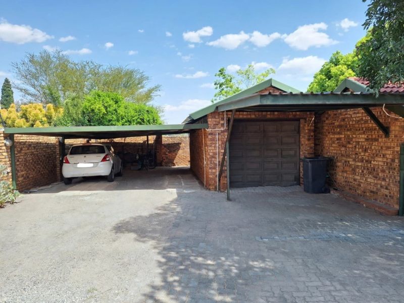 A brick-built garage with an attached carport providing covered parking space on a paved driveway.