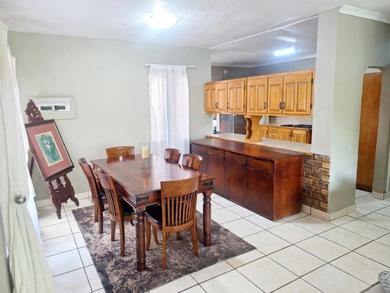 Open-plan dining area featuring tiled flooring and a built-in wooden cabinetry unit with a kitchen pass-through counter.