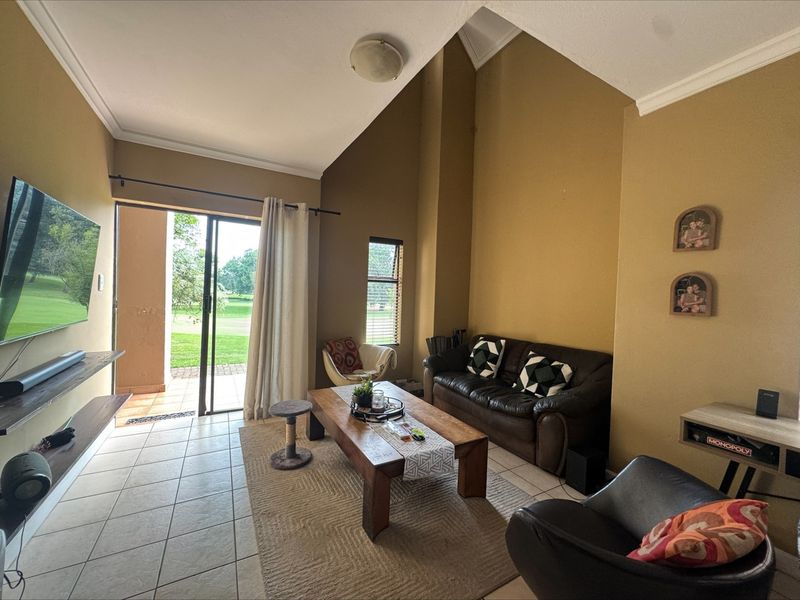 Spacious living room featuring high vaulted ceilings, ceramic tile flooring, and a large sliding glass door providing direct access to the outdoor patio area.