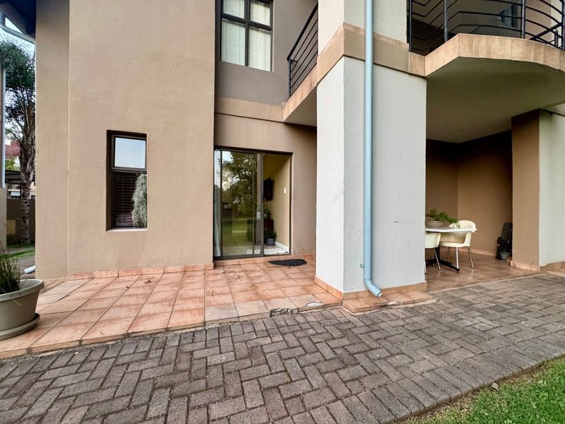 A ground-floor patio area featuring tiled flooring, a sliding glass door entrance, and a paved walkway, offering a functional outdoor space.