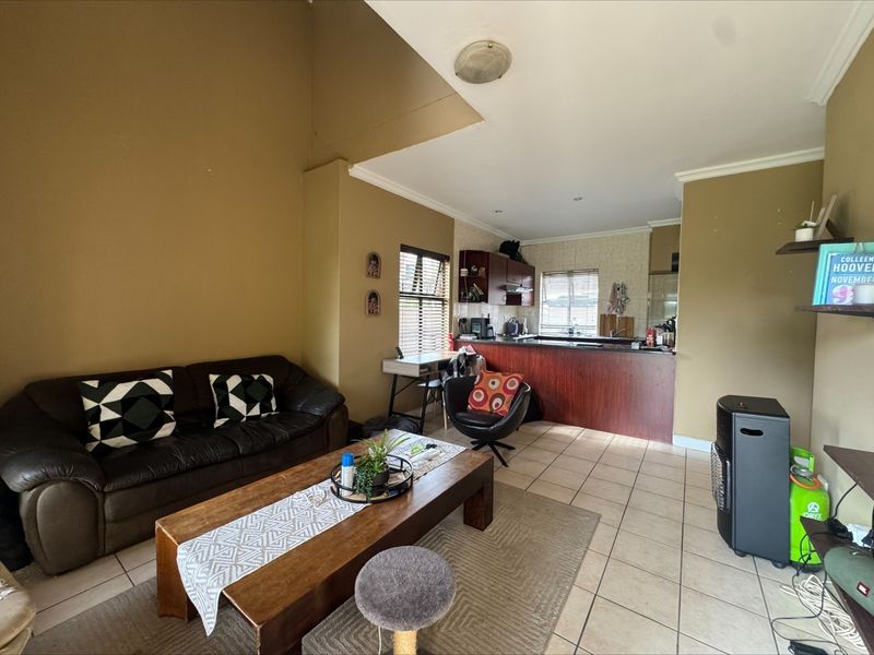 Open plan living and kitchen area featuring tiled flooring, breakfast bar, and neutral wall tones, offering a functional layout for modern apartment living.