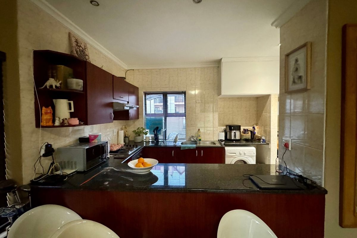 A functional kitchen featuring dark wood cabinetry, granite countertops, a tiled backsplash, and integrated appliances, offering a practical layout for daily cooking.