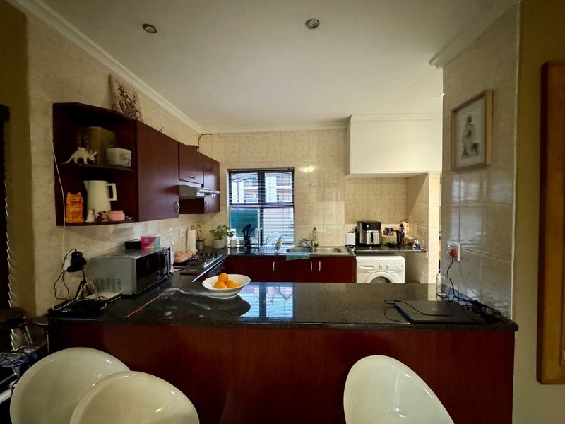 A functional kitchen featuring dark wood cabinetry, granite countertops, a tiled backsplash, and integrated appliances, offering a practical layout for daily cooking.