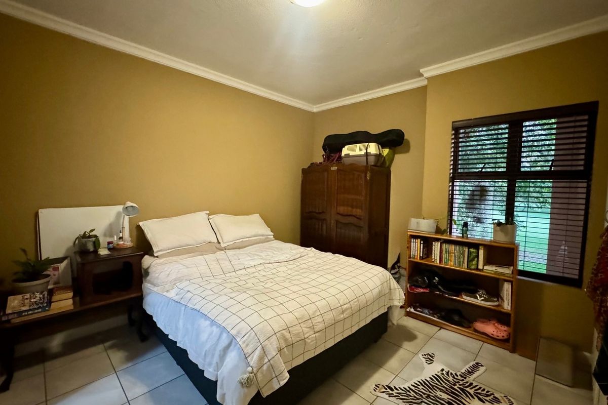 A bedroom featuring tiled flooring, neutral wall paint, and venetian blinds, offering a functional space with standard finishes.