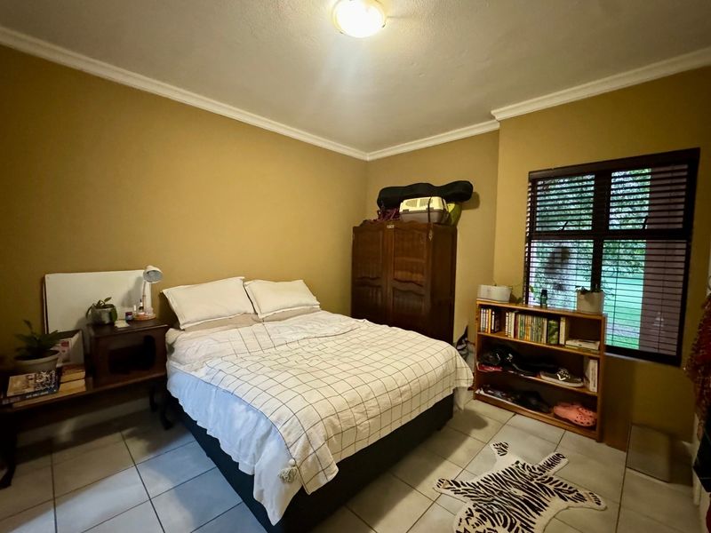 A bedroom featuring tiled flooring, neutral wall paint, and venetian blinds, offering a functional space with standard finishes.