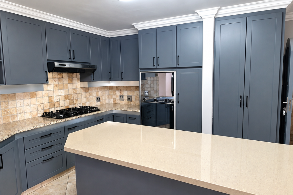 Modern kitchen featuring dark blue cabinetry, granite countertops, a central island, and a built-in gas hob with an extractor fan.