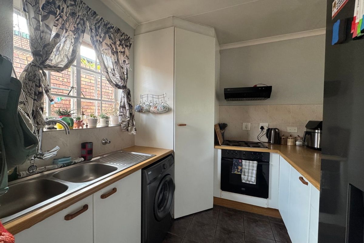 Compact kitchen featuring wooden countertops, built-in oven with extractor fan, double sink, and tiled flooring with ample storage cabinetry.