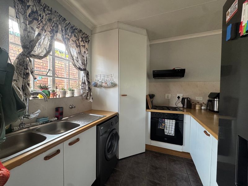 Compact kitchen featuring wooden countertops, built-in oven with extractor fan, double sink, and tiled flooring with ample storage cabinetry.