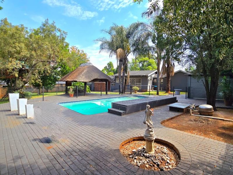 Outdoor pool area featuring a swimming pool, thatched lapa, and paved patio space, ideal for outdoor entertainment and relaxation.