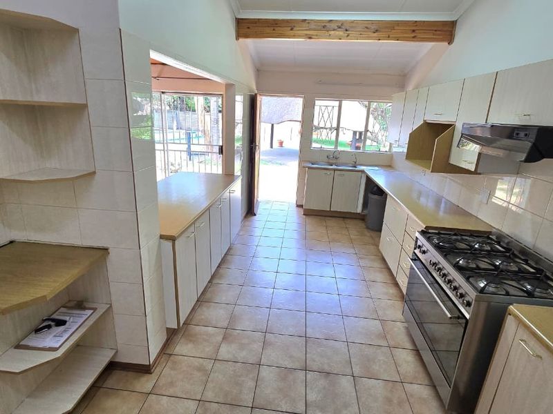 Spacious kitchen featuring tiled flooring, built-in cabinetry, a gas stove with extractor fan, and direct access to the outdoor area.