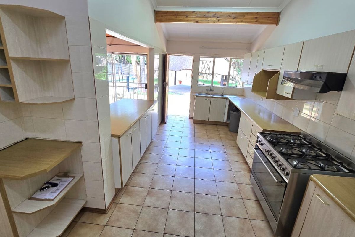Spacious kitchen featuring tiled flooring, built-in cabinetry, a gas stove with extractor fan, and direct access to the outdoor area.
