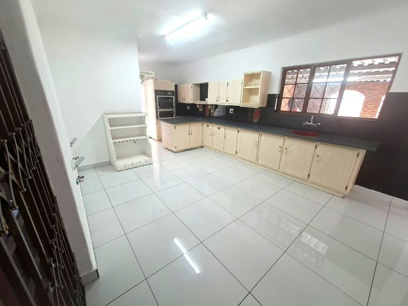 Spacious kitchen featuring built-in cabinetry, double wall oven, and tiled flooring. The area is clean and ready for modern updates.