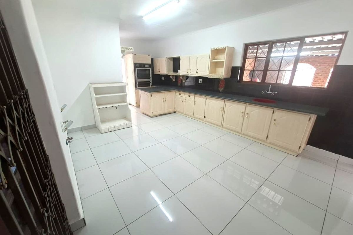 Spacious kitchen featuring built-in cabinetry, double wall oven, and tiled flooring. The area is clean and ready for modern updates.