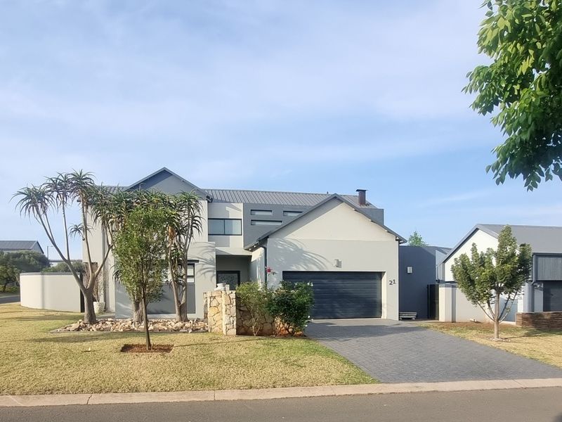 Modern double-story residential home featuring a paved driveway, double garage, and contemporary stone cladding accents on a well-maintained landscaped lot.