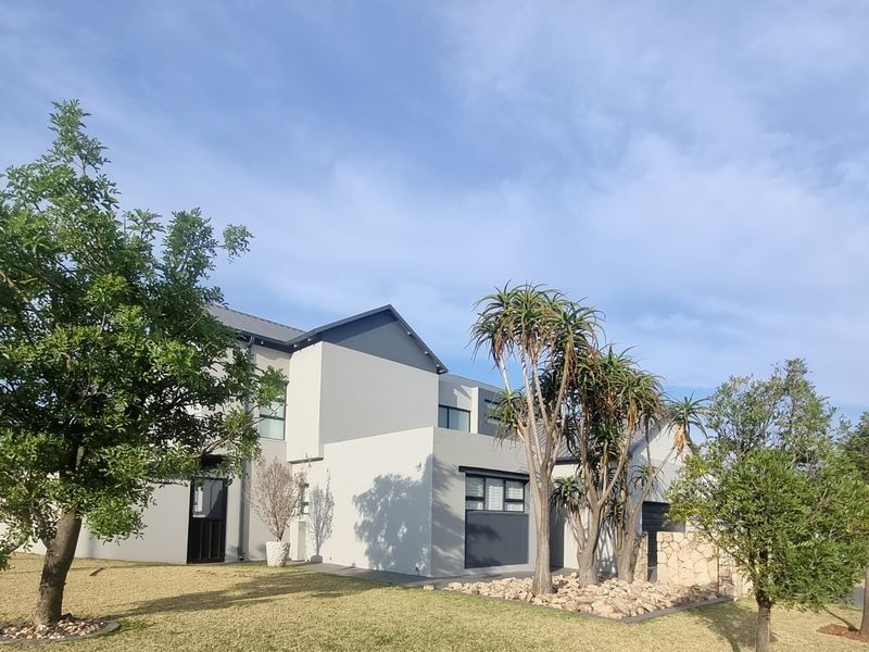 A modern double-story residential property featuring clean architectural lines, stone cladding accents, and a well-maintained landscaped garden.