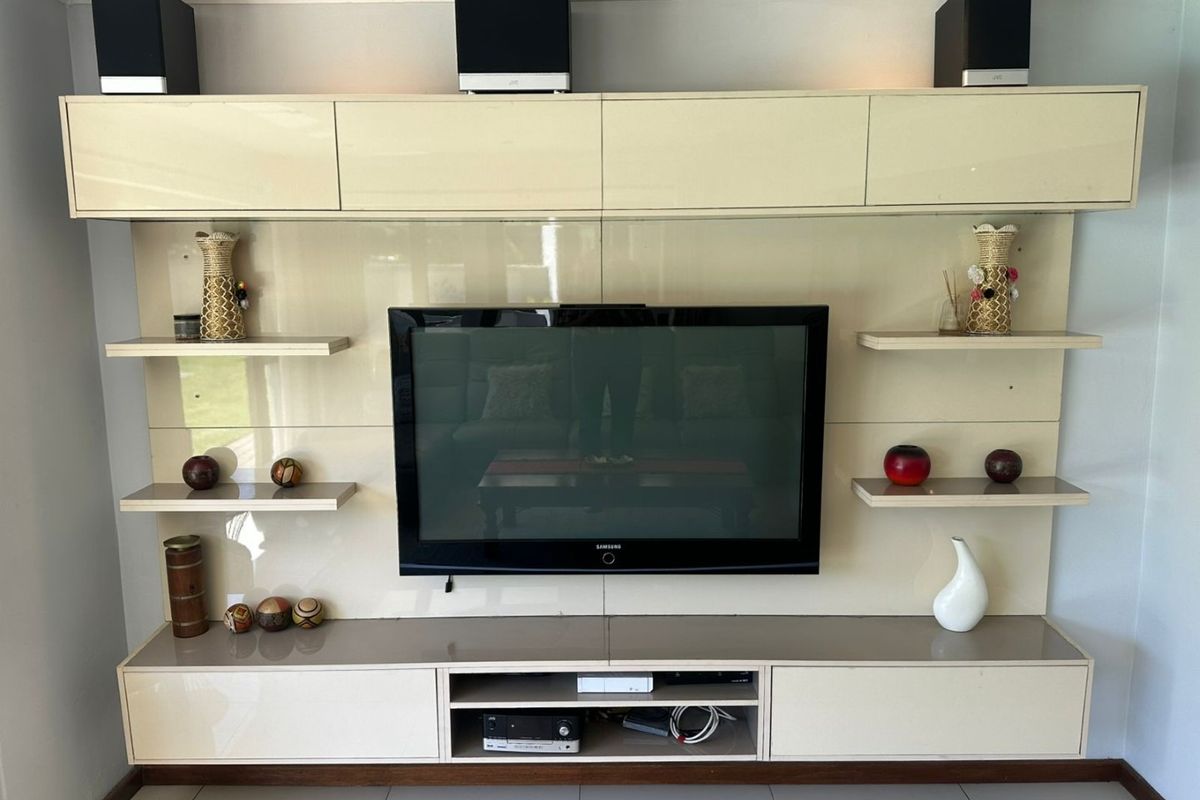 A modern living room featuring a sleek, high-gloss built-in media wall unit with integrated shelving and cabinetry.