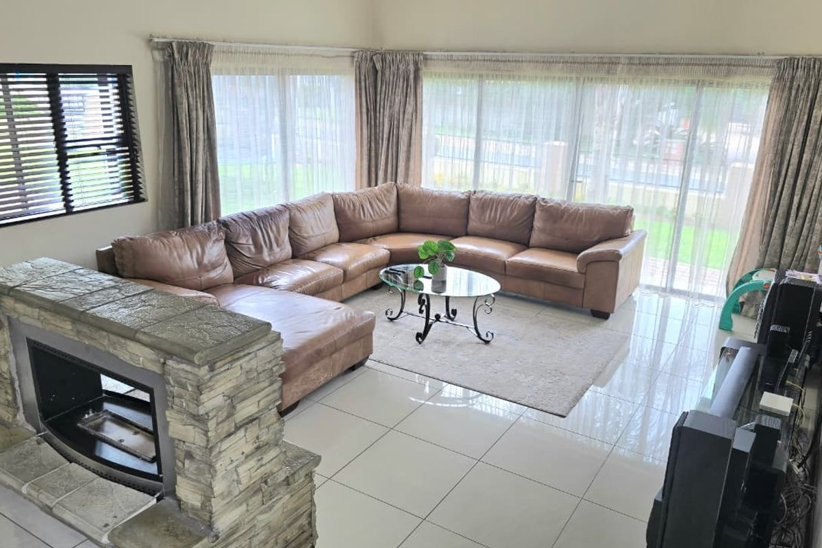 Spacious living room featuring polished tile flooring, a prominent stone-clad fireplace, and large sliding glass doors providing ample natural light.