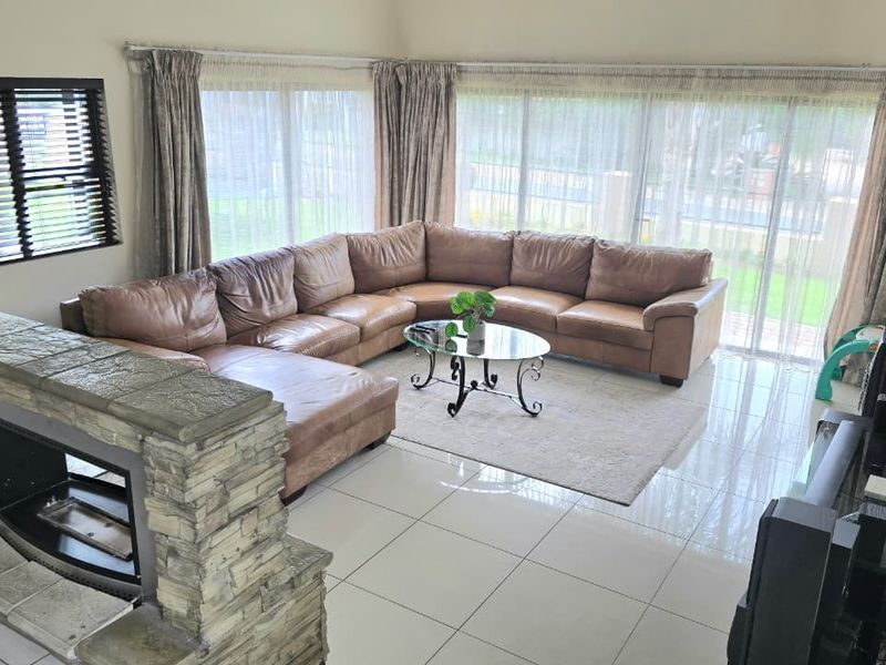 Spacious living room featuring polished tile flooring, a prominent stone-clad fireplace, and large sliding glass doors providing ample natural light.