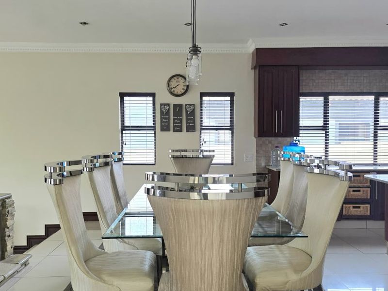 Open-plan living and dining area featuring a built-in fireplace, modern kitchen cabinetry, and tiled flooring, creating a cohesive and functional space.