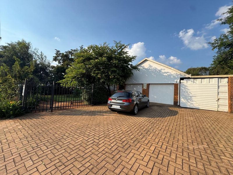 Front exterior view of the property featuring a paved driveway, double garage, and secure gated entrance.