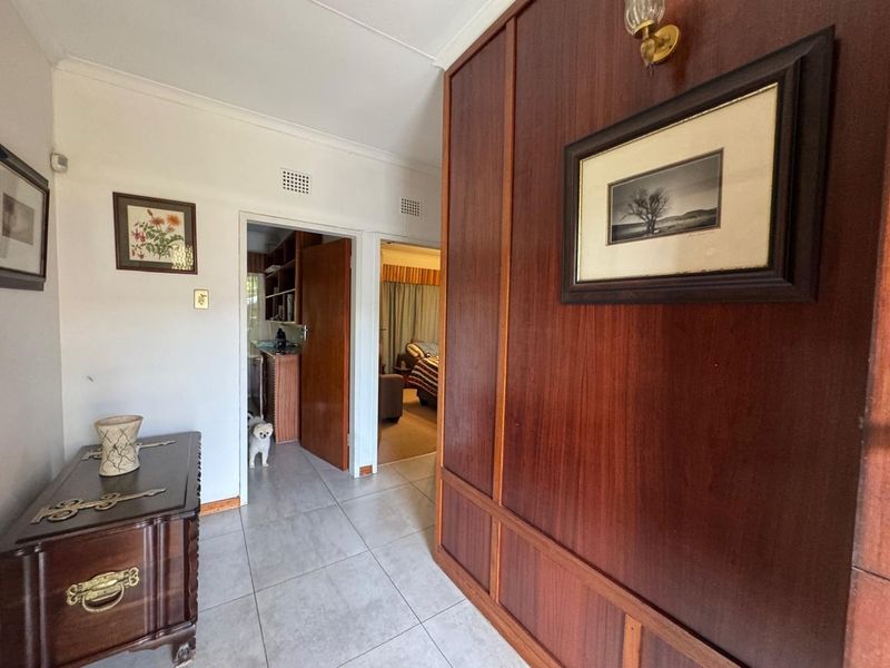 A hallway featuring wood paneling, tiled flooring, and access to adjacent rooms.