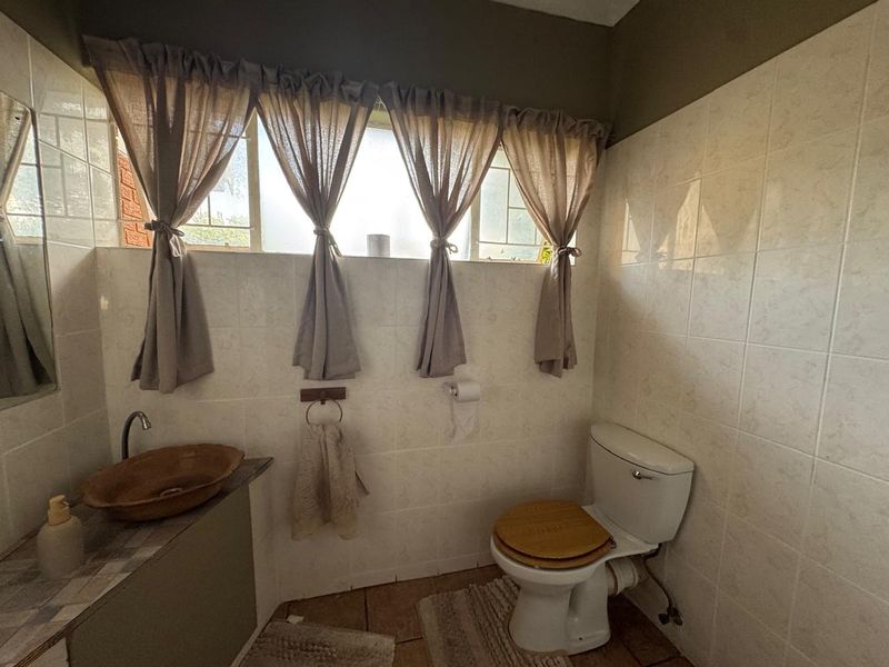 A functional bathroom featuring tiled walls and floors, a vessel sink vanity, and a standard toilet.