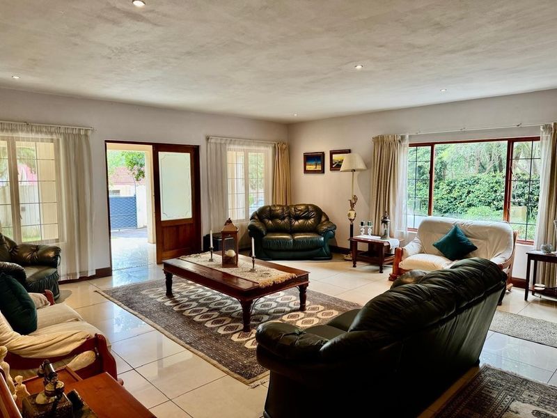 Spacious living room featuring tiled flooring, recessed downlights, and large windows providing natural light and access to the outdoor area.
