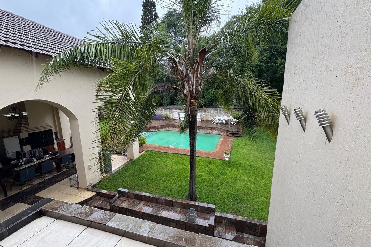 Rear view of the property featuring a covered patio, a swimming pool with brick surround, and a landscaped garden area.