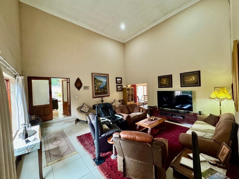 Spacious living room featuring high vaulted ceilings, tiled flooring, and direct access to an adjoining area through double doors.
