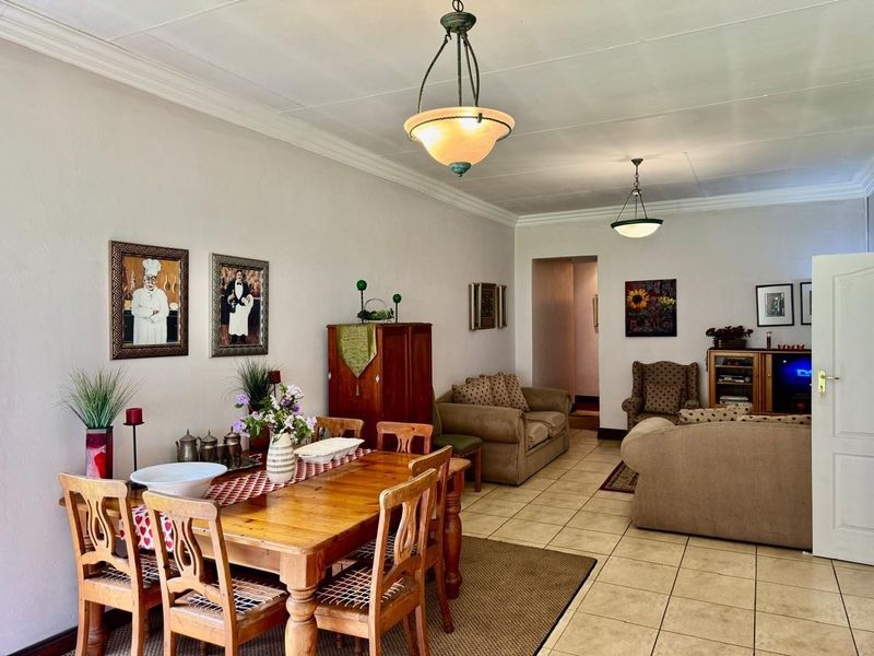 An open-plan living and dining area featuring tiled flooring, decorative ceiling molding, and pendant lighting fixtures.