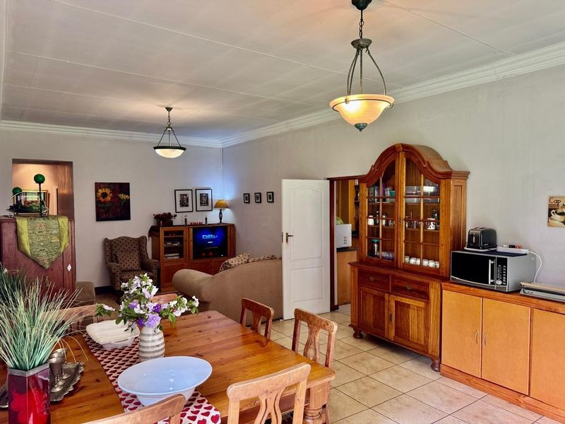 Open plan living and dining area featuring tiled flooring, coved ceilings, and pendant lighting, providing a functional and connected space for daily living.