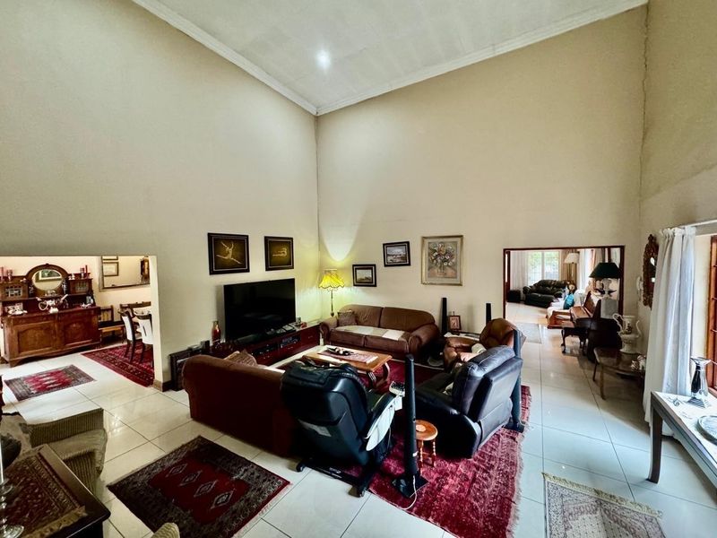 Spacious living room featuring high vaulted ceilings, tiled flooring, and open-plan access to adjacent dining and living areas.