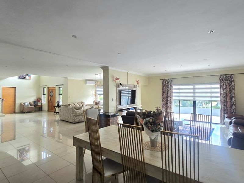 Spacious open-plan living and dining area featuring polished tiled floors, recessed lighting, and direct access to an outdoor patio through large sliding glass doors.