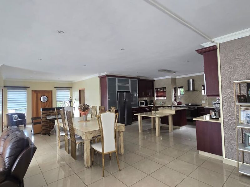 Spacious open-plan living and dining area featuring tiled floors, recessed lighting, and a well-appointed kitchen with built-in cabinetry and a central island.