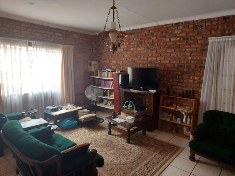 A rustic living room featuring exposed brick walls, tiled flooring, and a classic ceiling light fixture, offering a warm and traditional farm-style aesthetic.