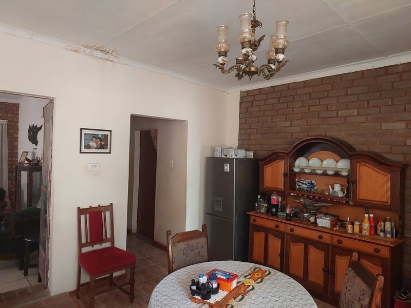 Dining area featuring an exposed brick wall, tiled flooring, and a classic chandelier, showing signs of ceiling water damage.