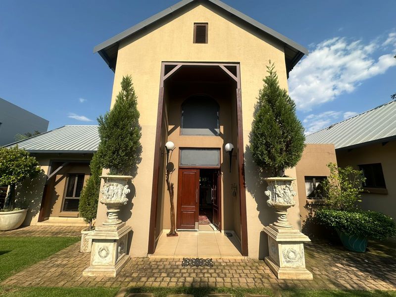 A well-maintained front entrance featuring a double-storey facade, timber door, and paved porch area, showcasing a classic architectural design.