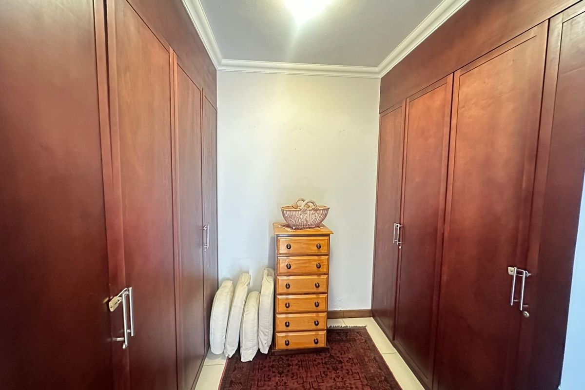 A bedroom featuring extensive floor-to-ceiling built-in wooden cupboards providing ample storage space.