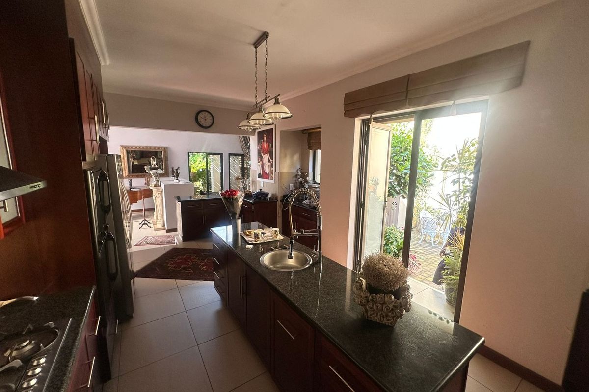 A well-appointed kitchen featuring a central island with granite countertops, dark wood cabinetry, and direct access to an outdoor patio area.