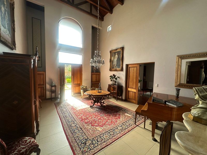 Spacious living area featuring high vaulted ceilings with exposed timber trusses, large arched windows, tiled flooring, and elegant timber door finishes.