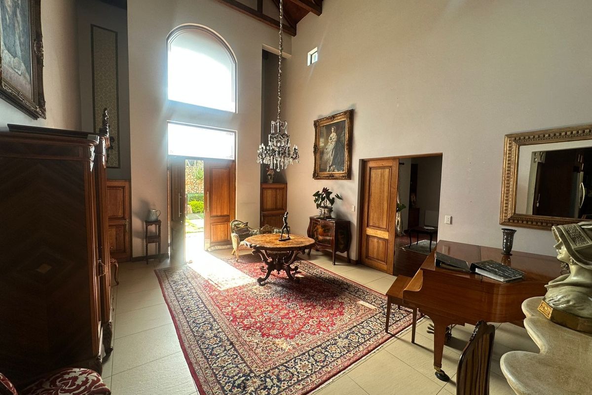 Spacious living area featuring high vaulted ceilings with exposed timber trusses, large arched windows, tiled flooring, and elegant timber door finishes.